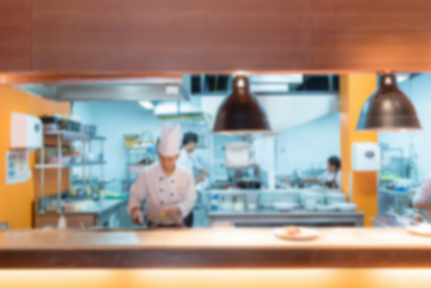 fire suppression kitchen Blurry view of chefs cooking in a restaurant kitchen under warm lighting.